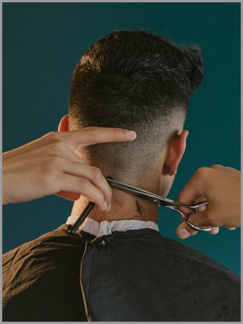 Hände einer Friseurin bei einem präzisen Haarschnitt mit Schere und Kamm